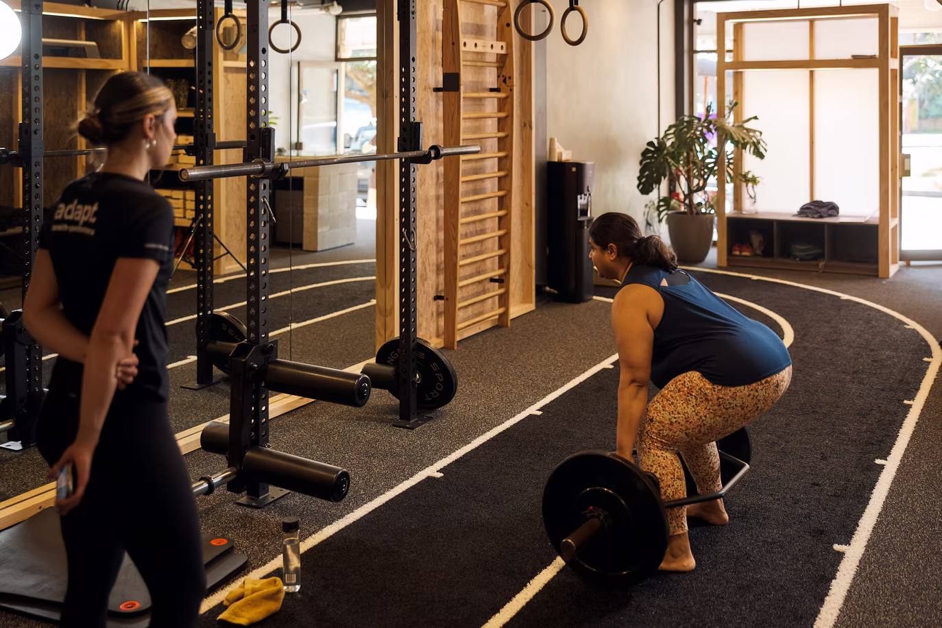 A coach guiding a client through a squat at Adapt, North Sydney